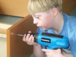 A_boy_with_Down_syndrome_using_cordless_drill_to_assemble_a_book_case.jpg